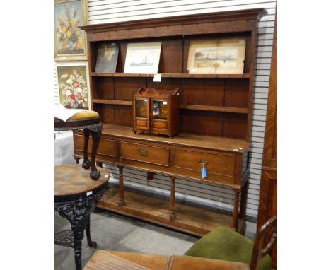 An oak Welsh dresser with three frieze drawers and open under-shelf supported by circular tapered supports, three-tier open p