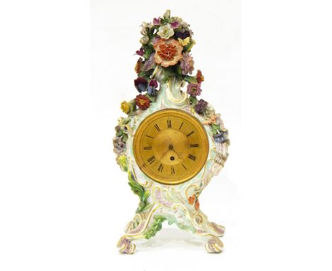 A continental Meissen style porcelain mantel clock, the case decorated with scrolls and applied flowerheads, on four shell an