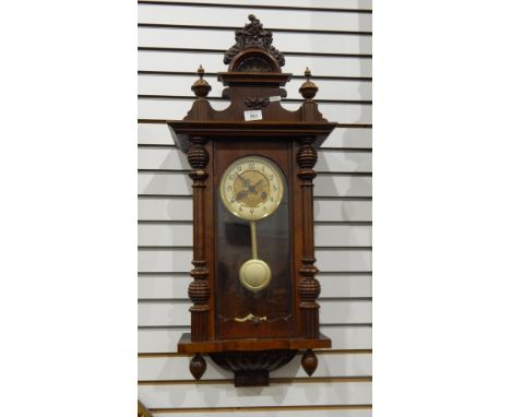 A stained walnut Vienna regulator style wall clock having ornate, foliate and floral pediment, flanked by pair of finials, tu