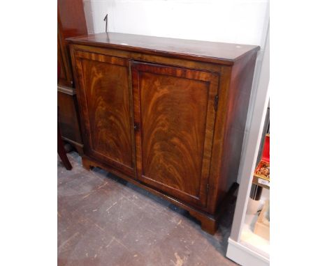 A early nineteenth century mahogany side cupboard, the pair of panelled doors, with matching frame mahogany pattern, enclosin