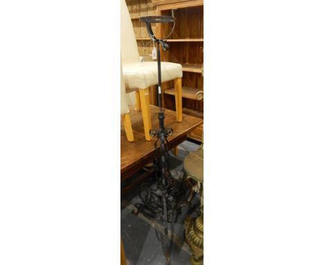 A wrought iron lamp stand on openwork tripod scroll base 