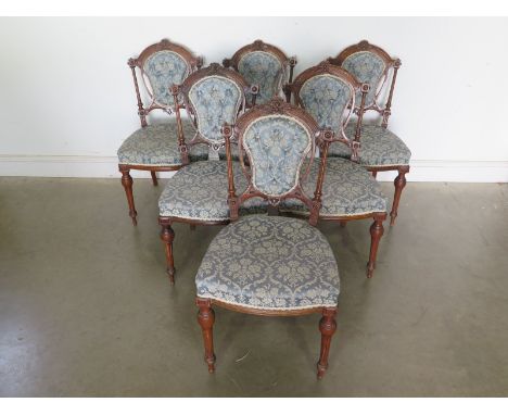 A set of six Victorian walnut salon chairs with button backs and overstuffed seats on fluted supports 