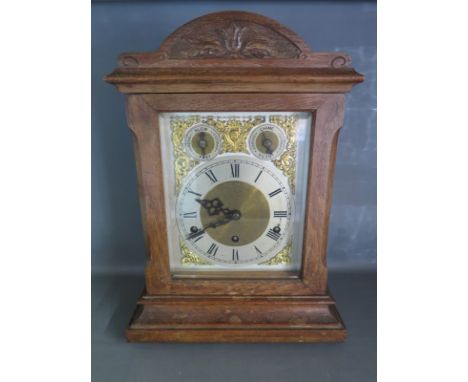 An oak cased mantle clock with brass spandrels and Roman numerals to dial, German movement with pendulum and key.