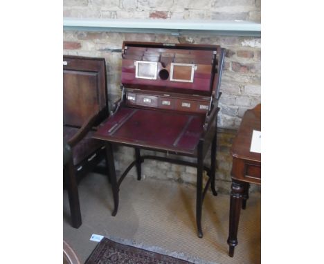 An Edwardian mahogany Campaign writing desk with lift up top  revealing a fitted interior of drawers, leather sleeves and pen