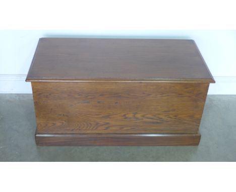 An oak stained trunk with lift up lid, twin brass side handles on plinth - 47cm x 96cm x 49cm 