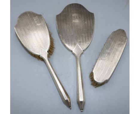 George V silver three piece vanity set to include two brushes and a mirror decorated with engine turned pattern, monogrammed 