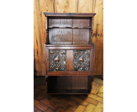 An early 20th century oak Art Nouveau wall hanging cabinet, with a recessed shelf above a cupboard door applied with a pair o