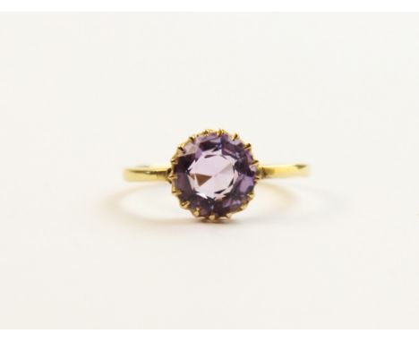 An amethyst coloured stone set 18ct gold ring, comprising a central round mixed cut purple coloured gemstone, 9mm diameter, (