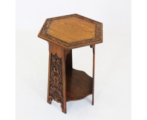 An early 20th century Arts and Crafts oak occasional table, the hexagonal top with a leaf carved frieze, raised upon three ta