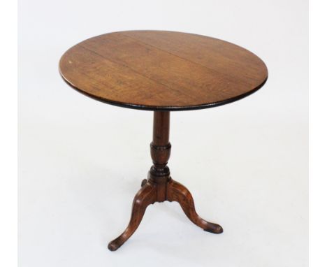 A George III oak tripod table, the circular top raised upon a ring turned tapering column and three down swept supports with 