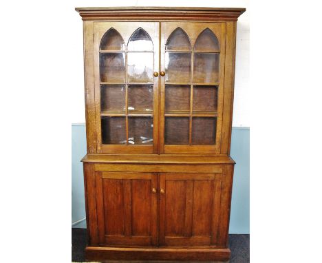 A 19th century honey oak library bookcase, the moulded cornice above a pair of arcaded glazed doors enclosing three shelves, 