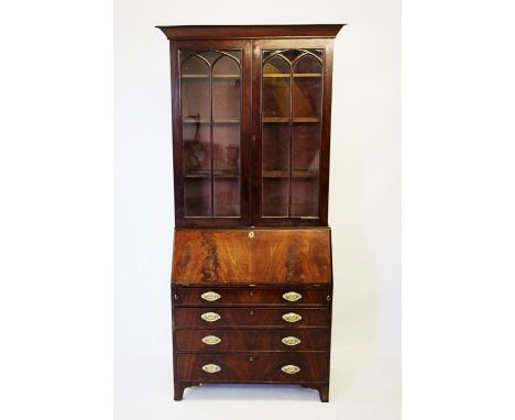 An early 19th century mahogany bureau bookcase, with a moulded tapering cornice above a pair of glazed doors, applied with Go