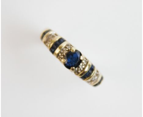 A sapphire and diamond 15ct gold ring, comprising a central oval mixed cut sapphire measuring 5mm x 3mm, claw set to tapering