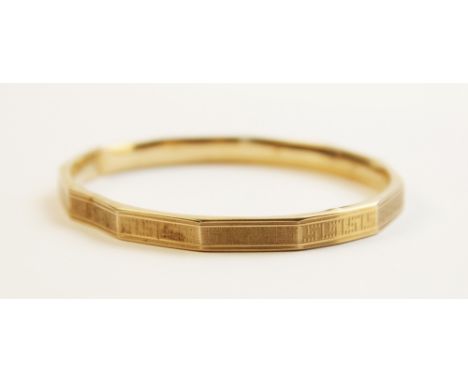 A 9ct gold faceted bangle, Chester 1911, with engine turned decoration to exterior, 7.8cm x 6.8cm, weight 9.2gms 