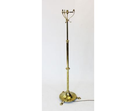 An early 20th century Art Nouveau brass standard lamp, the adjustable and graduated column raised upon a hammered circular pl