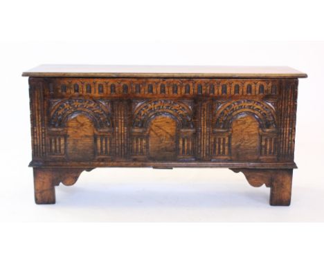 A 17th century style oak coffer, mid 20th century, the rectangular moulded top above a nulled frieze and three panels carved 