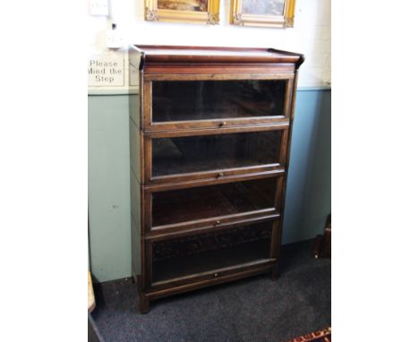 An early 20th century oak Globe Wernicke type stacking bookcase, the over hanging pediment above four 'up and over' glazed do