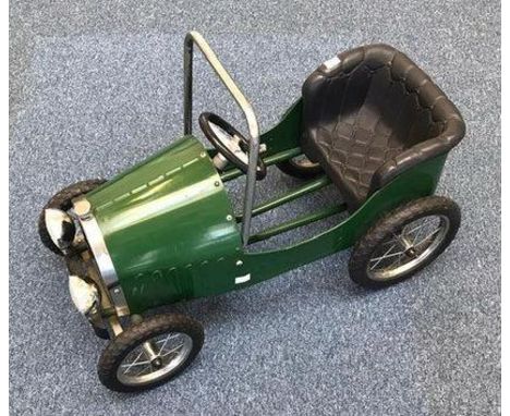 A child's green painted metal pedal car, modelled as a vintage motor car, with plastic moulded and quilted seat, chrome roll 