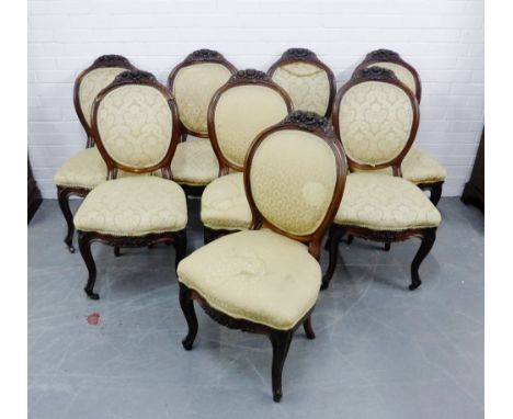 A set of eight Victorian rosewood parlour chairs, with oval shaped backs and carved floral cresting over pad seats, raised on