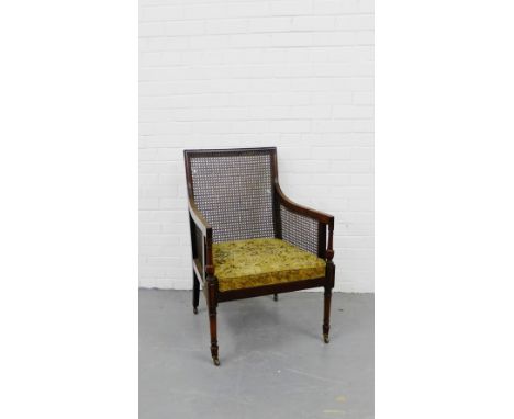 A mahogany framed armchair with canework back and sides, with a floral upholstered seat, on tapering supports terminating in 