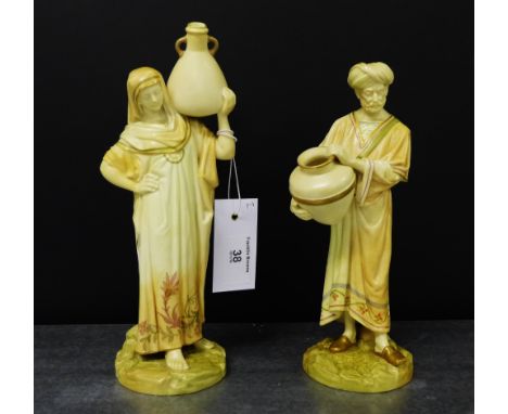 A pair of Royal Worcester blush ivory male and female water carrier figures, modelled standing on a naturalistic circular bas