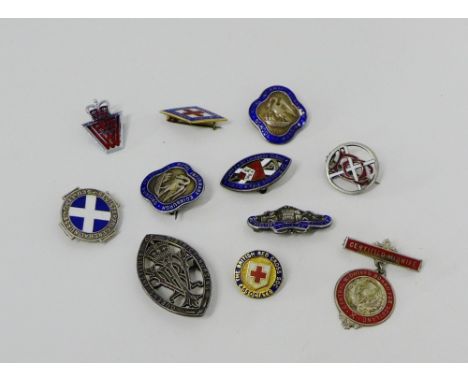 A collection of silver and enamel Nurses badges to include two Pelican examples together with vintage enamel badges (11)