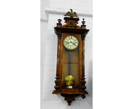 A mahogany cased Vienna wall clock, the pediment top surmounted by a carved wood eagle,  the enamel dial with Roman numerals,