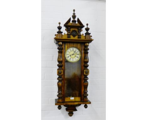 A mahogany cased Vienna wall clock, the broken pediment top over an enamel dial with Roman numerals, flanked by turned pilast