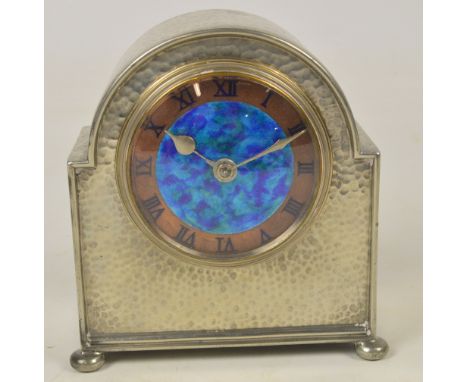 LIBERTY & CO; a Tudric hammered pewter dome topped mantel timepiece with central panel of blue/green enamel within a copper c