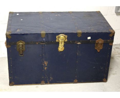 A large early 20th century dark blue metal travel trunk with black metal and brass trim and leather carrying handles, approx 