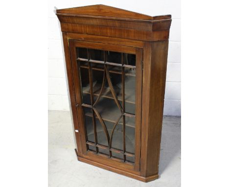 A Victorian mahogany corner cabinet with architectural pediment surmounting a single glazed door, opening to reveal three pla