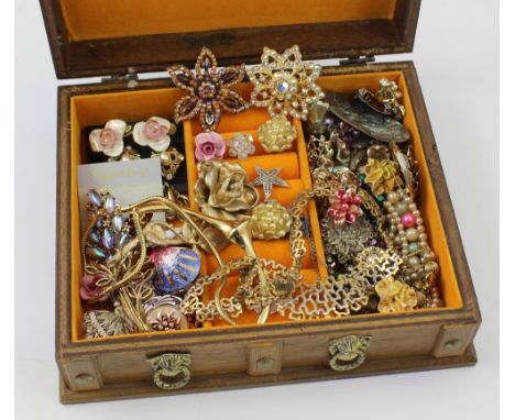 A wooden jewellery box containing a quantity of vintage jewellery to include diamanté brooches, gilt necklaces, earrings etc.