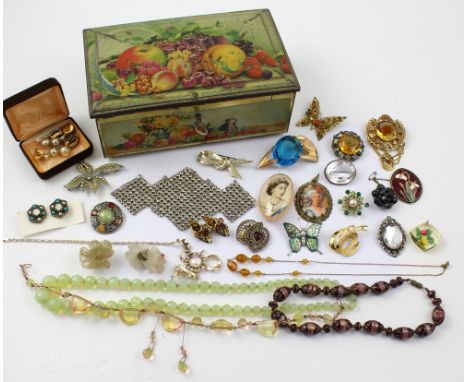 A vintage tin containing a quantity of assorted costume jewellery.