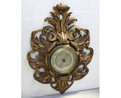 A Shortlands Smiths aneroid barometer of circular form in scrolling gilt acanthus and sea scroll mount, height 60cm. CONDITIO