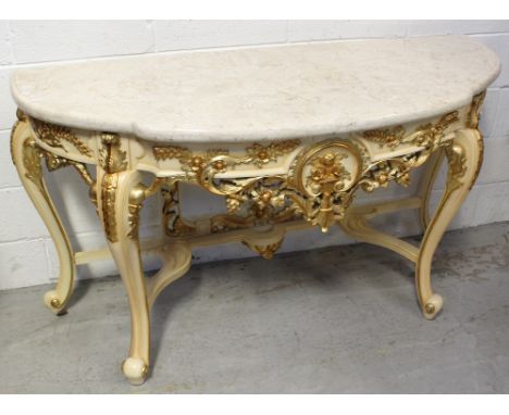 A contemporary ornate console table in the French style with composite marble top, gilded frieze of swags, leaves and flowers