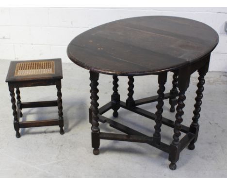 An early 20th century oak barleytwist gate leg table, length when extended 108cm, and a cane seated stool (2).