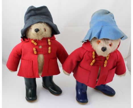 Two vintage Paddington Bear toys, both dressed in red duffel coats, one with green/blue Wellington boots and grey hat, the ot