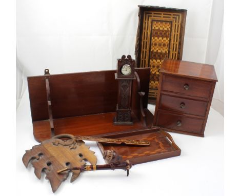 A mahogany miniature three drawer chest, height 28cm, two shelves, a pocket watch stand modelled as a longcase clock, two tra