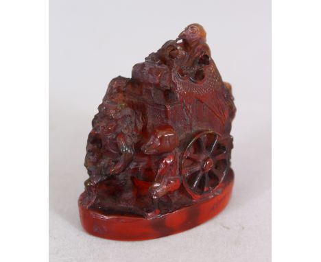 A 20TH CENTURY JAPANESE AMBER STYLE NETSUKE, carved in the form of a man with a cart accompanied by oni, tengu and a monkey, 