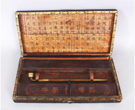 AN EARLY 20TH CENTURY CHINESE BRASS OPIUM PIPE, contained in a rectangular lacquered wood box with compartments and calligrap