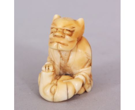 A JAPANESE MEIJI PERIOD IVORY NETSUKE OF A SEATED ONI, holding before him a Noh mask, 1.3in high.