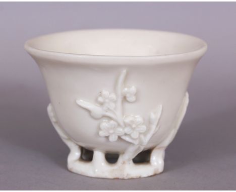 A CHINESE KANGXI PERIOD BLANC-DE-CHINE PORCELAIN LIBATION CUP, circa 1700, the sides moulded with sprigs of plum blossom, 2.9