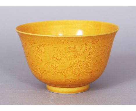 A GOOD QUALITY CHINESE YELLOW GLAZED PORCELAIN WINE CUP, the sides incised beneath the glaze with two dragons amidst flame an