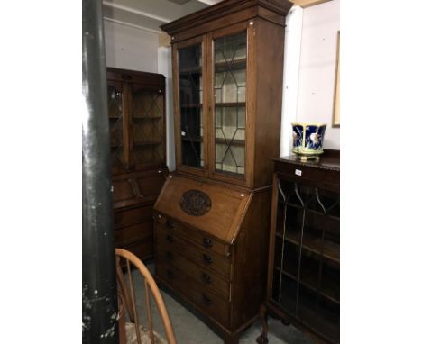 An oak bureau book case with carved panel.