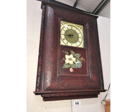 A carved wood framed wall clock with painted flower panel (Roman numeral clock face)