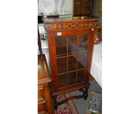 A glass panel fronted carved wood display cabinet