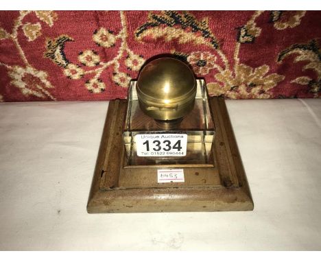 A glass inkwell on wooden base.