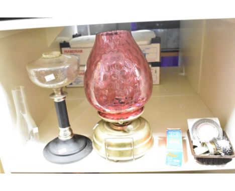 A late 19th Century brass oil lamp with cranberry glass shade, measuring 43cm high, together with a later oil lamp with cast 