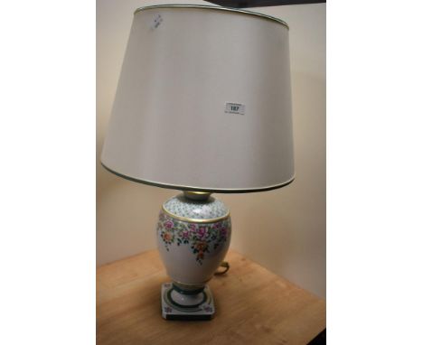 A 20th Century Italian porcelain table lamp, having a cream coloured shade, and floral decorated body, measuring 70cm tall