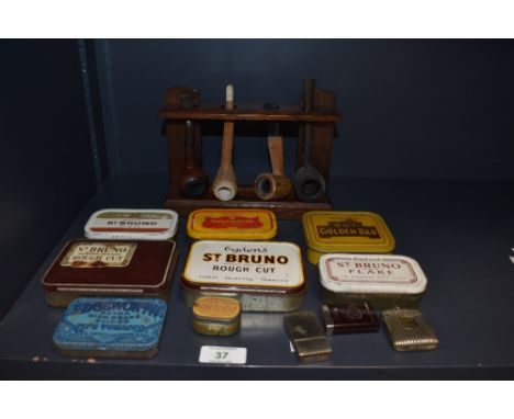 A selection of vintage tobacco  and snuff tins, three vesta cases and a pipe rack with four vintage pipes.